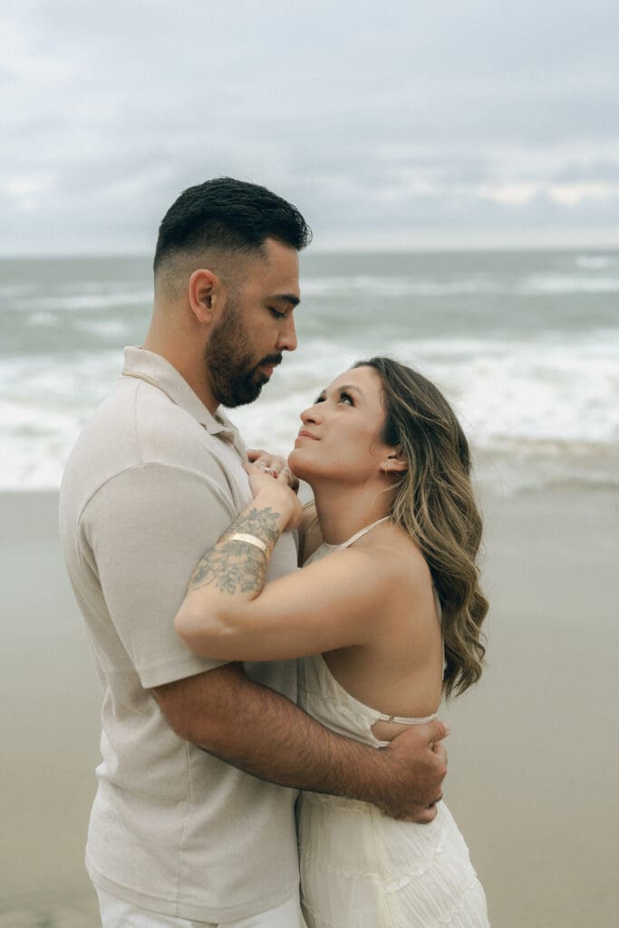What to wear for your beach engagement session in Laguna Beach: flowy dress catching the ocean breeze during sunset