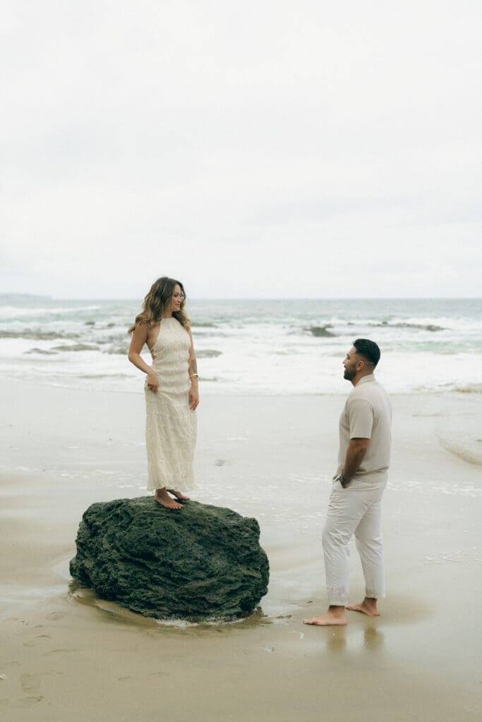 What to wear for your beach engagement session in Laguna Beach: couple holding hands in neutral tones by the tide pools