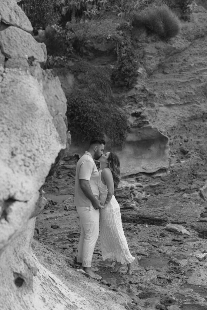 What to wear for your beach engagement session in Laguna Beach: couple walking barefoot on wet sand at Shaw’s Cove