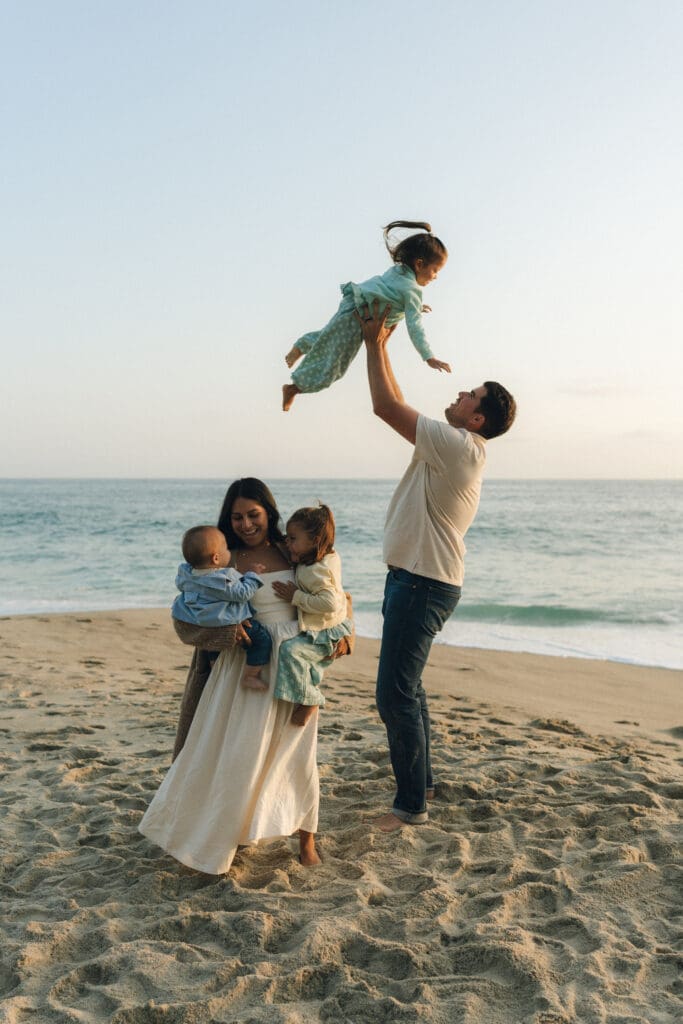 Dad throwing toddler in the air during a family beach photoshoot