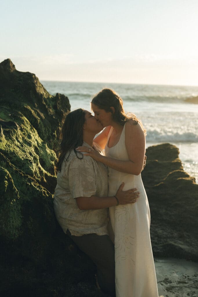 LGBTQ couple holding hands and laughing during beach proposal session