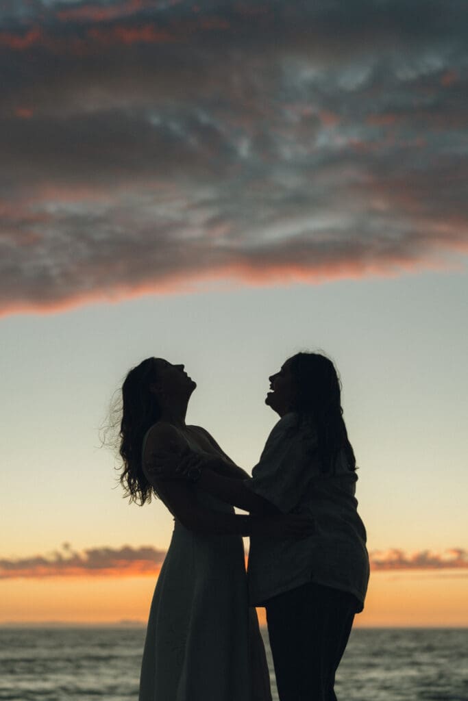 Couple celebrating engagement on the California coast during sunset